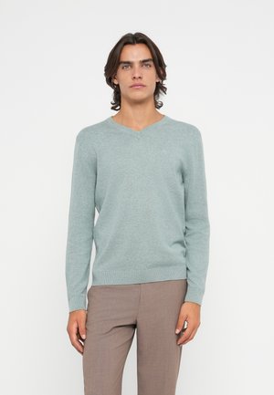 Helles türkisfarbenes V-Ausschnitt-Strickpullover aus weichem Material, mit langen Ärmeln und figurnahem Schnitt. Schlichte Textur ohne Muster.