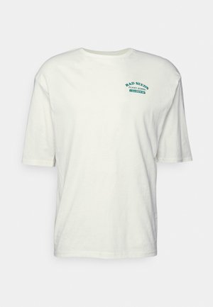 T-shirt blanc à manches courtes avec le texte vert "BAD SEEDS PLANT STORE 1-800-GROW-ON" sur la poitrine gauche.
