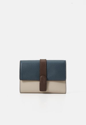 Leather wallet featuring a textured dark blue top, smooth light beige bottom, and a brown strap accent with a rounded closure.