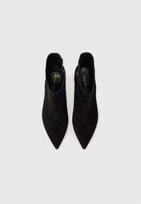 Bottines noires à bout pointu, en suède lisse, avec un détail de fermeture éclair sur le côté. Conçues pour une silhouette élégante.