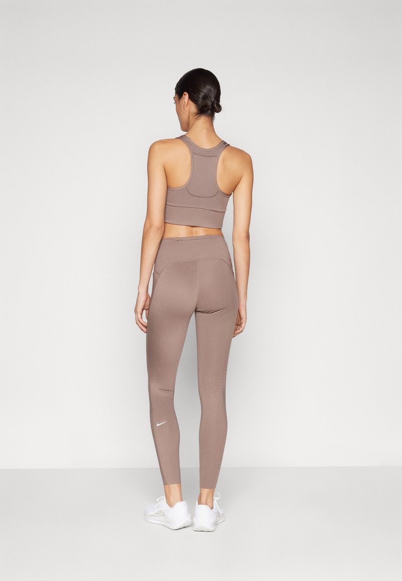 Soutien-gorge de sport marron et leggings assortis en tissu extensible, dotés d'un design avec dos nageur, d'une texture subtile, et d'une poche zippée au dos.