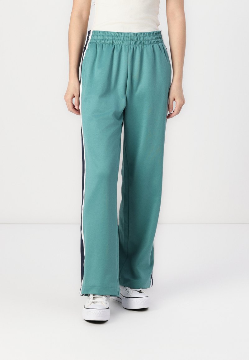 Teal joggebukser med en avslappet passform, med sidelister i marineblått og hvitt, elastisk midjebånd og myk bomullsblend. 