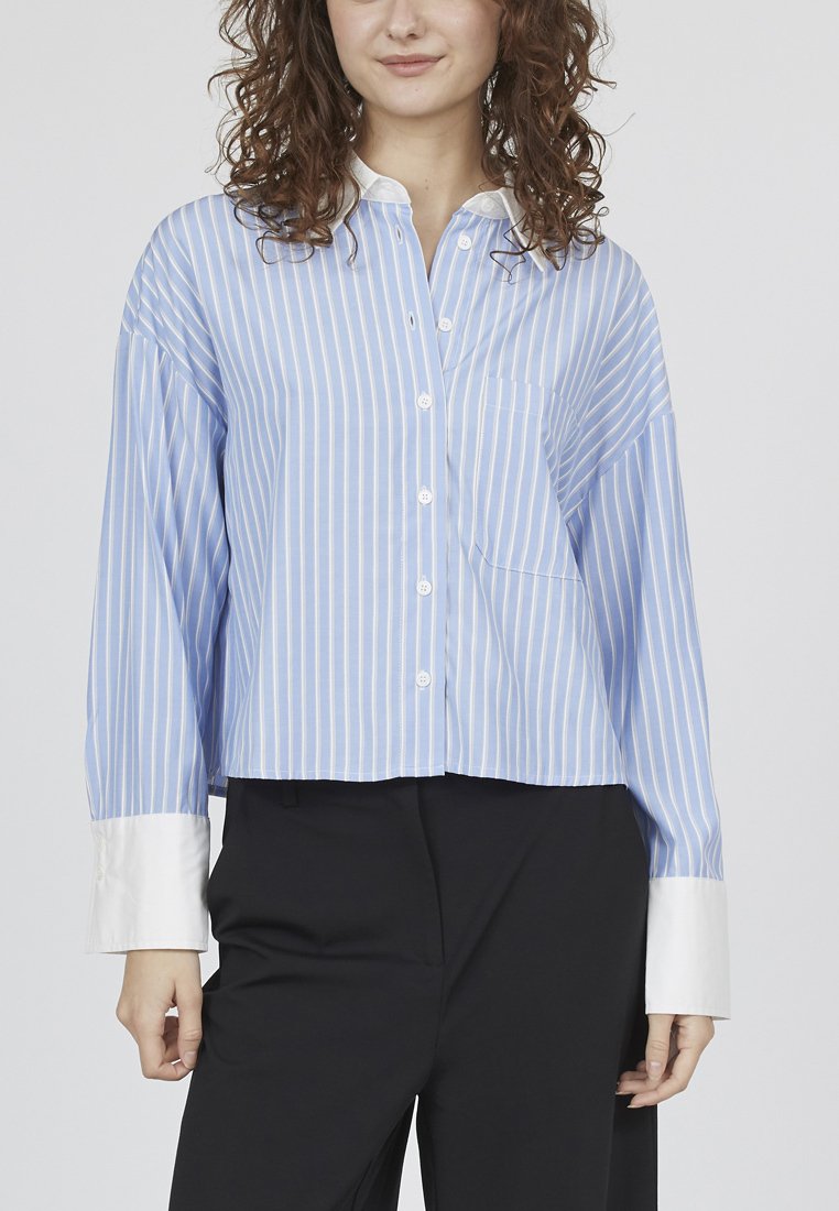 Lyseblå og hvidstribet, knappet skjorte med en cropped design, oversized ærmer og en hvid krave. Har en brystlomme.