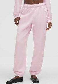 Rózsaszín, puha anyagból készült jogger nadrág, elasztikus derékkal és mandzsettákkal, oldalsó zsebekkel és laza szabással.