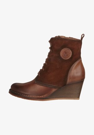 Botín de cuero marrón y ante con tacón de cuña, que presenta un parche redondo con el logo, cordones en la parte delantera y detalles de costura.