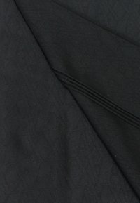 Tessuto nero con un sottile motivo geometrico, texture liscia e molteplici sezioni piegate. Adatto per abbigliamento o tappezzeria.