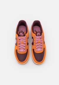 Nike Air Force 1-sneakers med en kombination av orange mocka, vinröd läder och rosa detaljer. Har perforerad tå och platta snören.