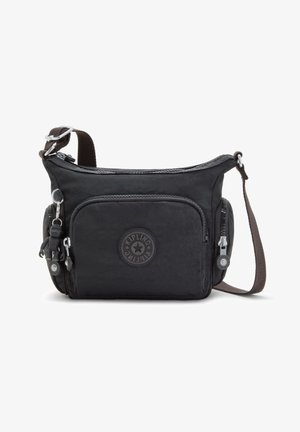Black fabric crossbody bag with two front zip pockets, a keychain embellishment, and a brown adjustable strap. Circular logo detail on front.