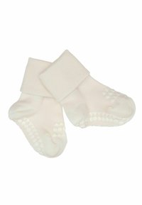 Chaussettes blanches pour bébé avec revers pliés et points antidérapants sur les semelles, présentées sur un fond blanc.