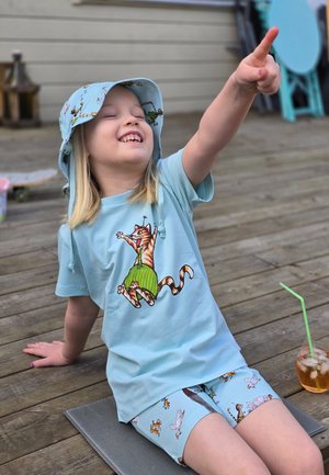 Vaaleansininen puuvillainen t-paita, jossa on sarjakuvakissan printti, samanväriset siniset shortsit eläinkuosilla ja sininen ämpärilippalakki.