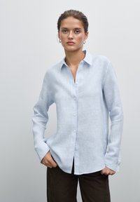 Camicia button-up azzurro chiaro in un tessuto morbido, con maniche lunghe, colletto classico e una vestibilità rilassata con una texture sottile.