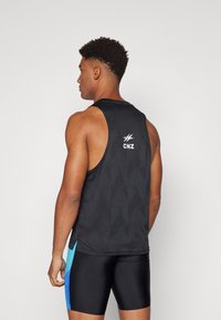 Black athletic tank top with a textured pattern, featuring a logo on the back and blue accents at the side, worn with black shorts.