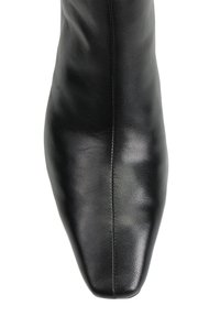 Czarny skórzany botek sięgający kostki z ostrym noskiem i gładką fakturą. Charakteryzuje się minimalnym przeszyciem i eleganckim designem.