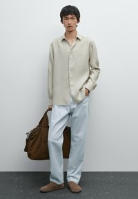 Beige linen long-sleeve shirt, light blue wide-legged trousers, brown suede slip-ons, and a brown shoulder bag with silver hardware.