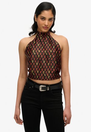 Czarny crop top na ramiączkach z kwiatowym wzorem w kolorach czerwonym, żółtym i czarnym. Zestawiony z czarnymi jeansami o wysokim stanie i srebrną klamrą pasa.
