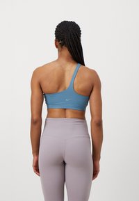 Blå en-skulder sport-bh i glatt stoff med lette sømmer; paret med høy midje, lavendel leggings med sømløst design.