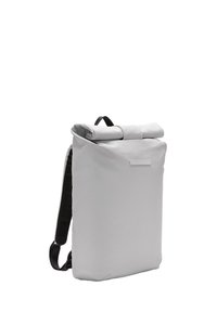 Sac à dos à rabat gris en tissu durable, doté de bretelles noires et d'un design minimaliste avec une poche avant et une base plate pour la stabilité.