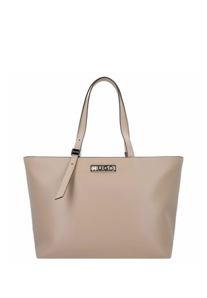 Bolso tote de cuero beige con dos asas, correa ajustable y logo metálico "HUGO" en el centro frontal.