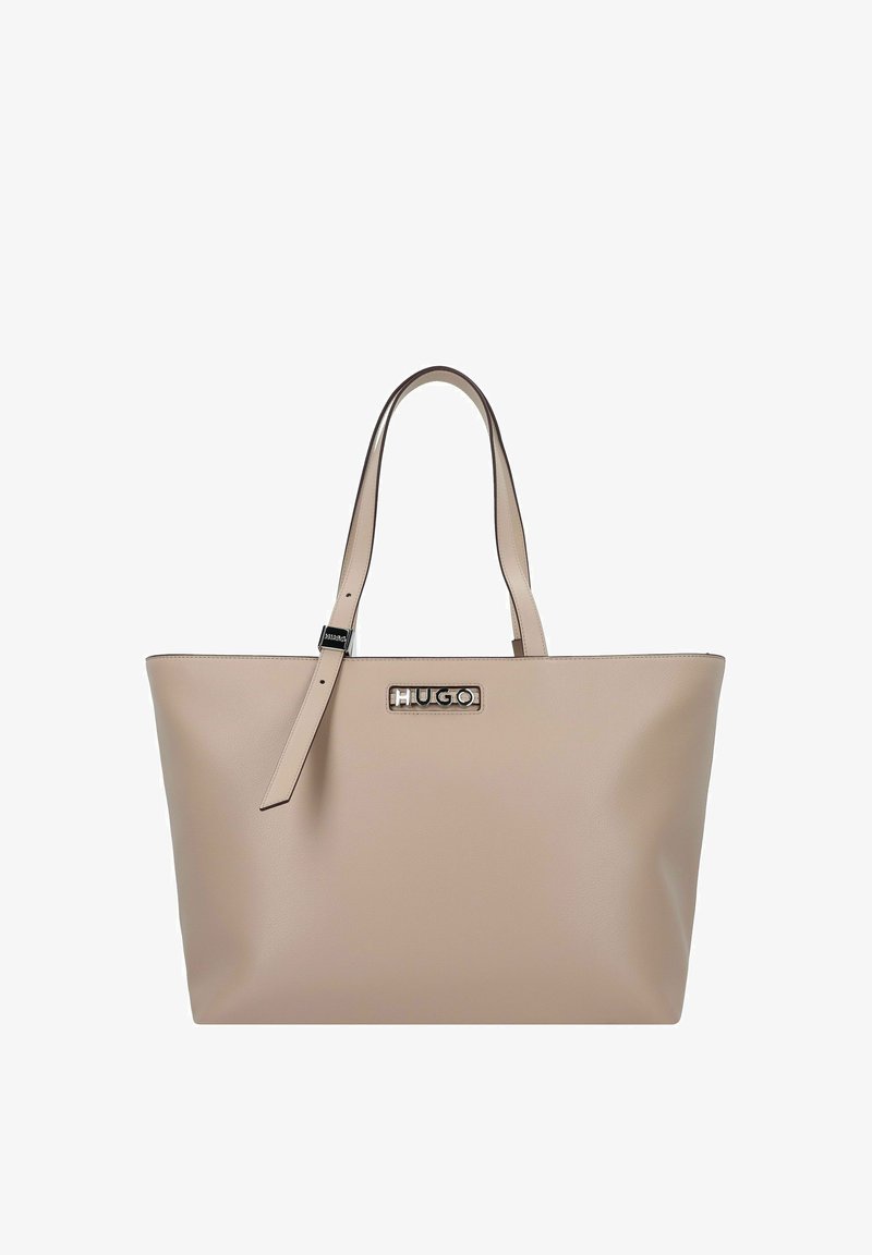 Sac tote en cuir beige avec deux anses, bandoulière ajustable et logo métallique "HUGO" au centre devant.