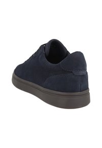 Zapatilla de ante azul marino con un diseño de perfil bajo, puntera redonda, cuello acolchado y suela de goma negra. Costuras visibles que realzan la parte superior.