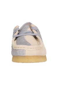 Chaussure en daim gris et beige avec bout arrondi, design à lacets, accents texturés et semelle en caoutchouc.