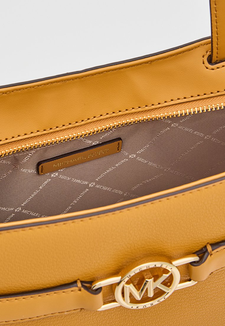 Sac à main en simili cuir jaune avec un détail logo circulaire doré, doté d'une fermeture éclair et d'un intérieur doublé avec un motif logo.