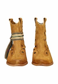 Botines color cuero de ante con diseños circulares recortados, suelas planas y tela a rayas envuelta alrededor de una bota.