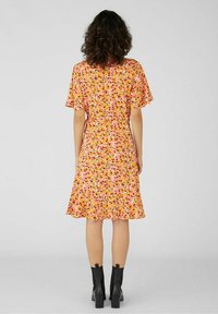 Kukallinen mekko, jossa on lyhyet liehuvat hihat, kireä vyötärö ja röyhelöhelma. Värit sisältävät vaaleanpunaista, oranssia ja vihreää vaalealla taustalla.