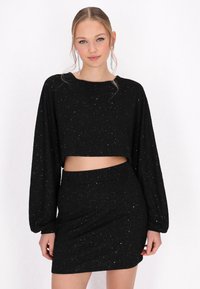 Schwarzes Zweiteiliges Set mit einem kurzärmligen Oberteil und einem enganliegenden Minirock, beide mit einer strukturierten Oberfläche und mehrfarbigen Glitzerakzenten.