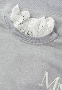 Grijze trui met geribbelde halslijn. Voorzien van een witte kanten rand die uit de kraag piept. Geborduurde "M" in het wit aan de voorkant.