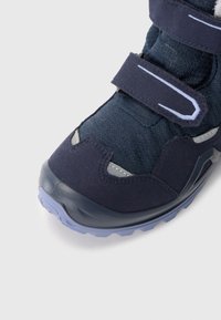 Schoen met een marineblauwe winterlaars met textiele bovenkant, klittenbandsluitingen en rubberen zool. Voorzien van grijze en lavendelkleurige accenten, een gevoerde kraag en een gestructureerd lichaam.