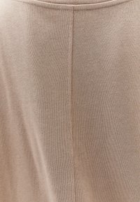 Beige Strickstoff mit glatter Textur und einer vertikalen Mittelnaht. Einfaches Design ohne zusätzliche Muster oder Akzente.