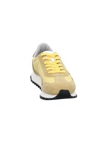 Sneaker giallo e beige con lacci gialli, suola intermedia bianca, battistrada nero e fodera interna grigia, mostrato da un angolo frontale su sfondo bianco.