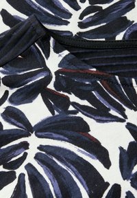 Černá a námořnická modrá látka se vzorem listů na bílém pozadí. Hladká textura s žebrovaným detailem kolem výstřihu.