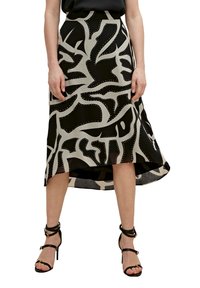 Een zwart en beige rok met een abstract ontwerp, voorzien van uitsparingen en zilveren studs, die net onder de knie eindigt met een subtiele high-low zoom.