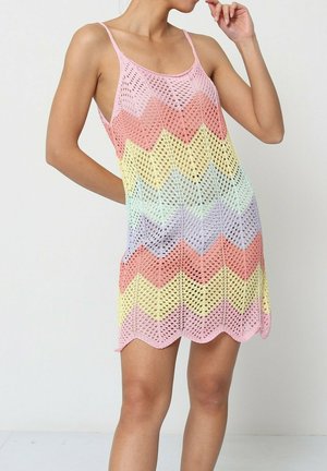 Robe au crochet de couleur pastel avec un motif en chevrons, dotée de fines bretelles et d'un ourlet festonné. Fabriquée en matériau léger et respirant.