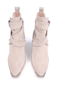 Botines de ante beige con punta afilada, que presentan una correa decorativa con costura envolviendo el eje y detalles en metal plateado.