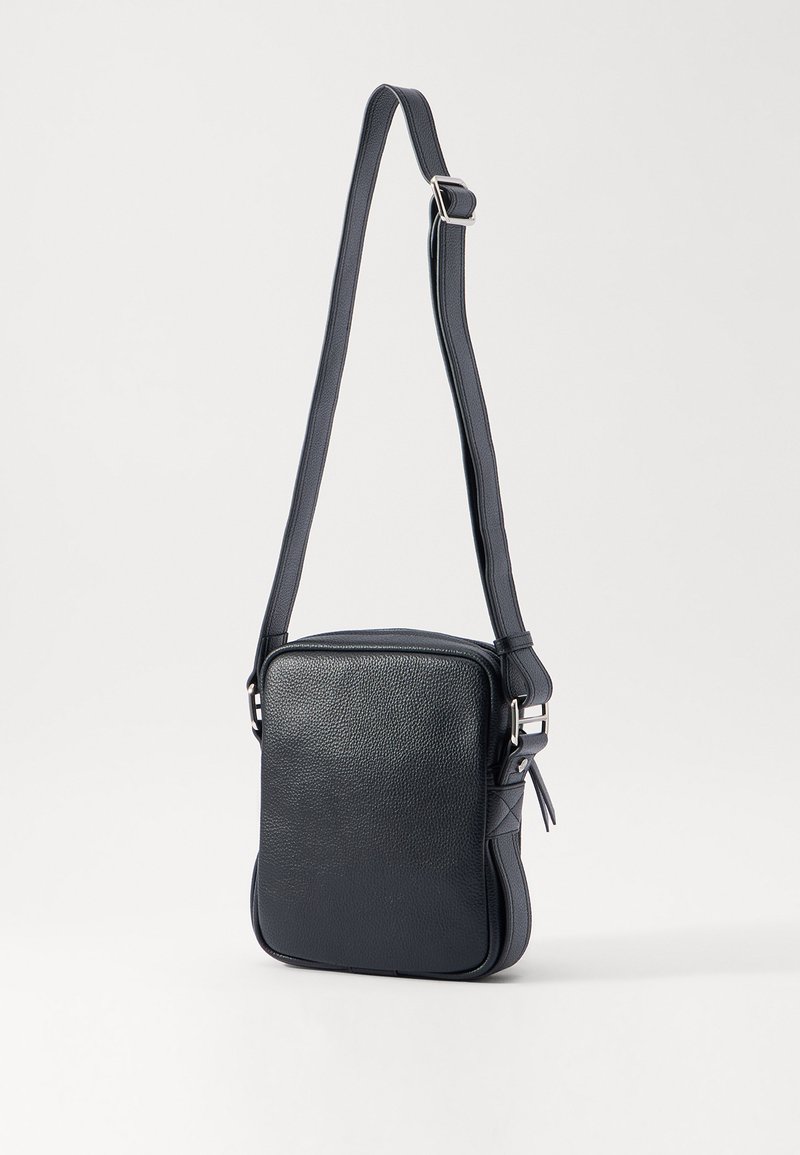 Donkerblauwe leren crossbody tas met een rechthoekige vorm, gestructureerd oppervlak, verstelbare schouderband en accenten in zilverkleurig metaal.