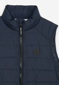 Marineblaues isoliertes Weste mit hohem Kragen, Frontreißverschluss und logo-patch. Verfügt über eine gesteppten Struktur und ärmelloses Design.