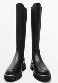 Bottes noires en cuir hauteur genou avec une finition lisse, une semelle épaisse et des panneaux élastiques latéraux pour un enfilage facile, dotées d'une conception à bout arrondi.