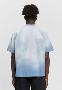 Blue ombre short-sleeve t-shirt with a relaxed fit. Fabric has a soft texture, fading from light blue at the top to darker blue at the bottom.