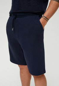 Shorts bleu marine en tissu doux, dotés d'une taille à cordon réglable, de poches latérales et d'un ourlet droit.