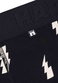 Crne bokserice s bijelim uzorkom munje. Elastični pojas s teksturiranim logotipom i oznakom za informacije o veličini.