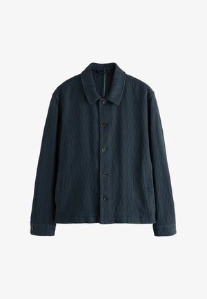 Dunkelblaues cordjackett mit spitzem Kragen, Knopfleiste vorne und zwei seitlichen Taschen. Verfügt über eine vertikale Rippstruktur.