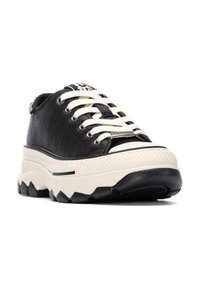 Zapatilla de piel negra con cordones blancos, suela de plataforma texturizada y mediopie de crema en contraste. Presenta un logo en la lengüeta y detalles de costura.