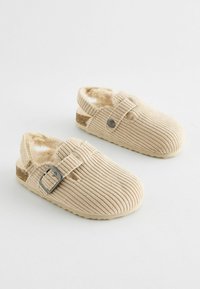 Beige kordflors slippers med en mjuk, lurvig foder, justerbar spänne och texturerad överdel. Rundad tå och baklös design.