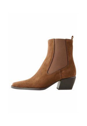 Brown suede ankle boot with elastic side panels, pointed toe, and a block heel. Textured accents on the heel enhance design.