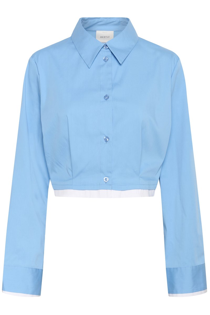 Chemise bleu clair coupée avec manches longues, col pointu et bordure blanche à l'ourlet et aux poignets.