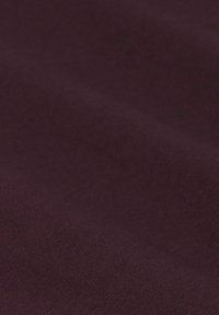 Close-up van zacht, donkerbruin stof met een subtiele textuur en zachte plooien, die het gladde oppervlak van het materiaal benadrukt.