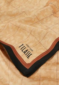 Sciarpa beige con stampa di mappa, caratterizzata da linee a griglia, bordo scuro e un accento marrone. Logo ricamato in nero nell'angolo inferiore.